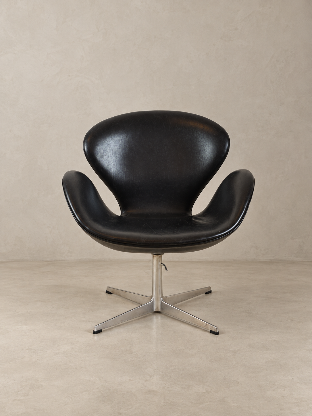 Symmetrical front view of a restored mid-century black leather Swan chair by designer Arne Jacobsen.